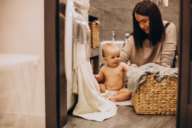 家庭主妇妈妈带着小女儿在家洗衣服帮助女儿快乐的女人