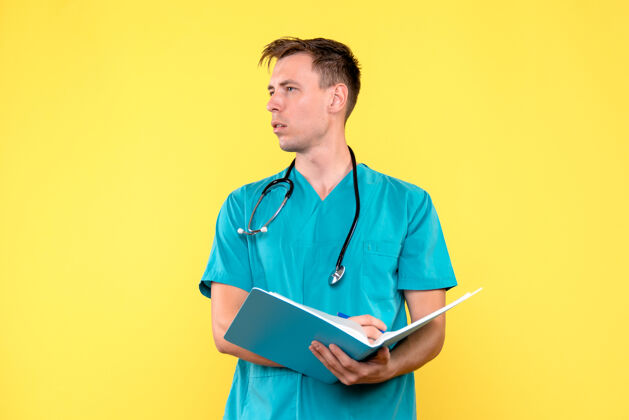 药前视图中的男医生拿着分析文件在黄色的墙上医疗医生护士