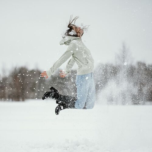 快乐在冬天的雪地里 女人在户外跳跃的侧视图姿势冬天户外