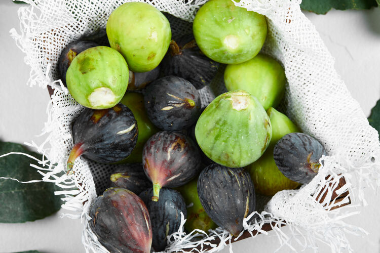 产品绿色和紫色的无花果放在一块粗麻布上的托盘里极简食物素食