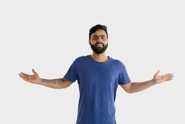 表情美丽的男性半身肖像隔离在白色的工作室背景年轻感性的印度教男子在蓝色衬衫面部表情 人类情感 广告概念介绍和邀请手势惊喜衬衫