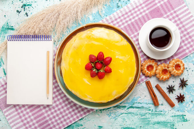 茶俯瞰美味的蛋糕用黄色糖浆新鲜的红色草莓和一杯茶放在蓝色的表面饼干蛋糕烤甜甜的糖派蛋糕糖浆午餐