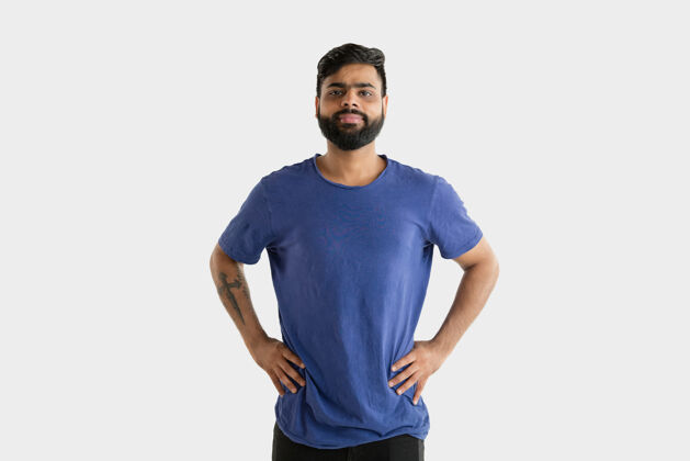 表情美丽的男性半身肖像隔离在白色的工作室背景年轻情绪化的印度教男子在蓝色衬衫面部表情 人类情感 广告概念站立和微笑消极手势站立