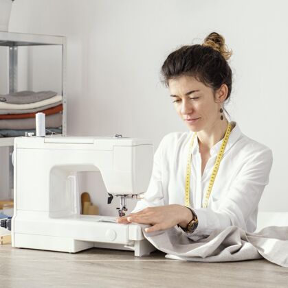 服装女裁缝用缝纫机工作的正面图服装师女士缝纫