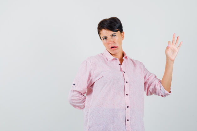成人女性展示ok手势 在粉色衬衫前视图中伸出舌头疾病肖像护士