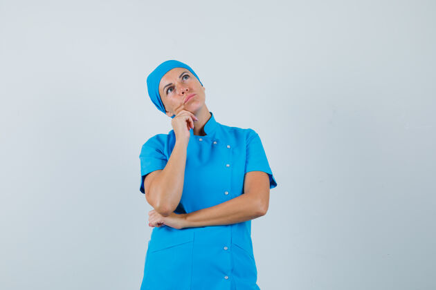 制服女医生手托下巴 身穿蓝色制服 面带沉思 俯视前方护士治疗疾病
