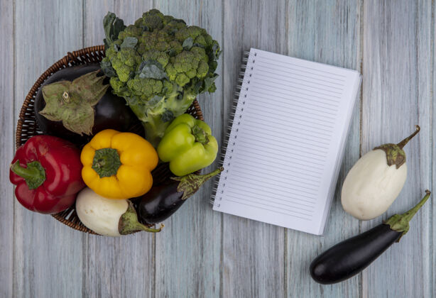 西兰花蔬菜的侧视图 如花椰菜 胡椒和茄子 放在篮子里 木制背景上有便笺簿 有复印空间食物笔记茄子