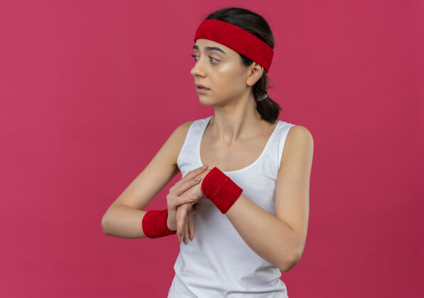 年轻身穿运动服的年轻健身女 戴着头巾 站在粉色的墙上焦急地热身女人担心站