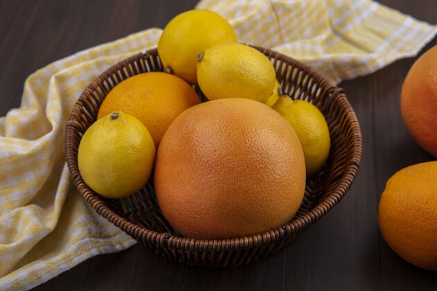 前面前视图柠檬与橙色和葡萄柚在篮子与黄色方格毛巾木制背景篮子葡萄柚风景