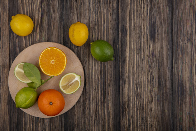 复制顶视图复制空间石灰一半与橙色一半的立场与柠檬在木制背景上食物顶部水果