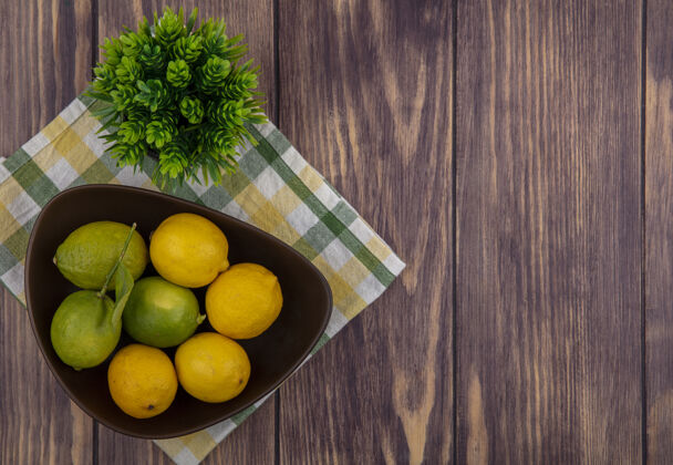空间顶视图复制空间柠檬与酸橙在一个黄色的绿色格子毛巾在一个木制背景碗酸橙碗木头