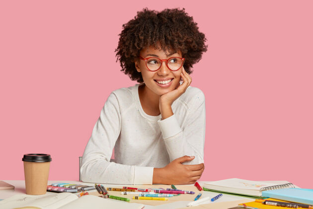 建筑师心满意足可爱开朗快乐的女设计师在咖啡休息时间梦想着一些令人愉快的事情 手放在脸颊上 穿着白色的套头衫 创造新的项目 隔离在粉红色的墙上素描人桌面