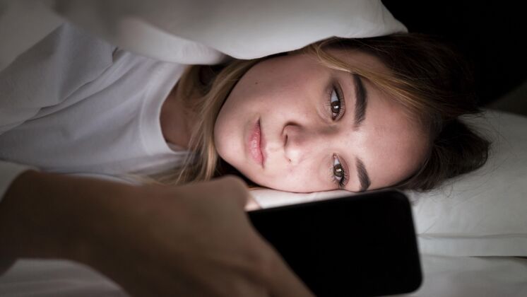 水平女孩晚上在床上用手机写真设备年轻人科技