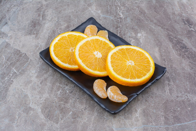 柑橘橘子和橘子片放在黑盘子里切块柑橘切片