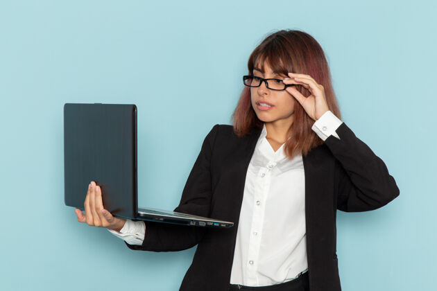 工作正面图：穿着正装的女上班族在蓝色表面上使用笔记本电脑西装笔记本电脑工人