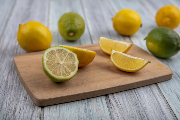 橘子侧视图与半橙色和柠檬在砧板上的石灰楔壁板食物盘子