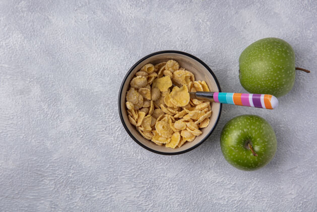 勺子顶视图复制空间玉米片在碗与汤匙和绿色苹果的白色背景顶部副本麦片