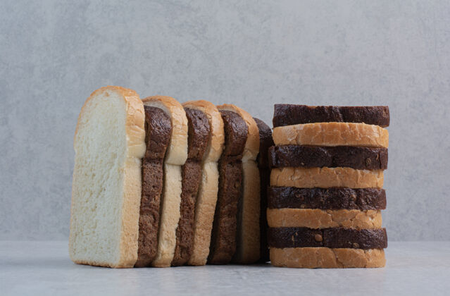 棕色新鲜的白色和棕色面包片放在大理石背景上食品烘焙小吃
