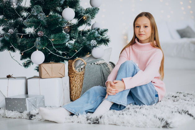 开放的礼物坐在圣诞树旁的小女孩庆祝圣诞快乐圣诞礼物