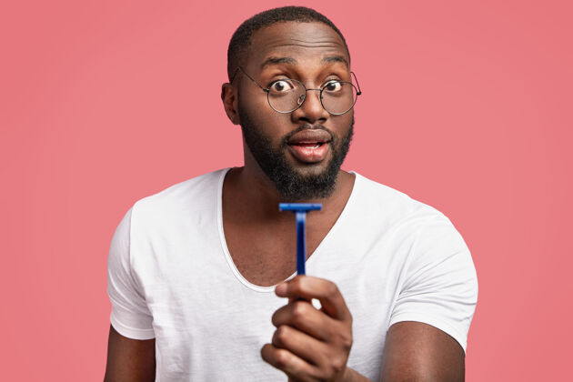 吸引皮肤黝黑 留胡须的非洲男性手持rasor广告皮肤护理卫生墙壁