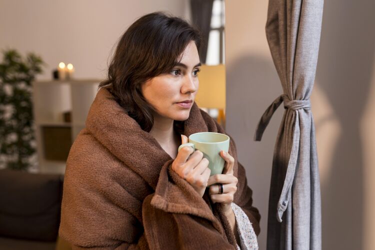 生活方式一个拿着一杯咖啡 身上裹着毯子的女人北欧风格斯堪的纳维亚舒适