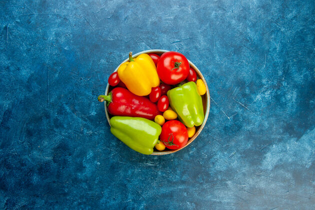 颜色顶视图新鲜蔬菜不同颜色的甜椒西红柿樱桃西红柿在碗里蓝色的桌子上有复制空间新鲜蔬菜铃铛胡椒