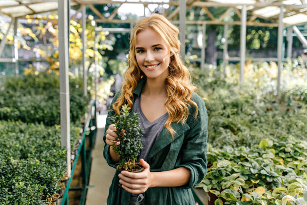 爱好绿眼睛红头发的女孩热爱大自然可爱的模特微笑着摆姿势 手里拿着植物植物学家配件享受