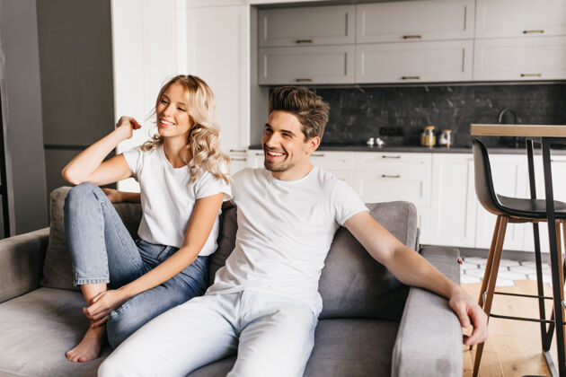 情人一对微笑的情侣坐在现代公寓的沙发上看电视快乐的年轻人和他美丽的女友在家里放松浪漫在一起男人