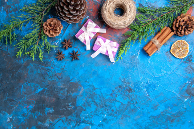 粉红色圣诞礼物顶视图粉色圣诞礼物松树枝桂枝八角干柠檬片蓝色表面免费空间彩色干肉桂