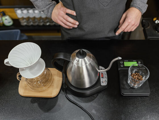 咖啡师高角度的男咖啡师用水壶和过滤器准备咖啡职业职业工作