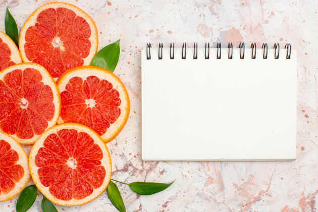 葡萄柚片俯瞰美味的柚子片裸体桌上的记事本维生素酸葡萄柚