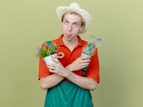 植物年轻的园丁 穿着连体衣 戴着帽子 手里拿着盆栽植物锅帽子举行