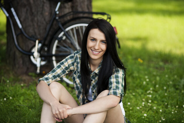 问美丽的年轻女子在公园休息草地女性自行车