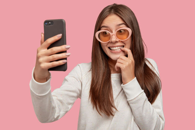 阴影内容微笑的欧洲年轻女子通过智能手机发送约会应用程序自拍皮肤照片健康