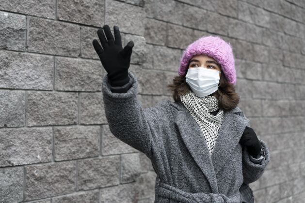 流行病戴着医用口罩的女人在城里挥手新常态人病毒