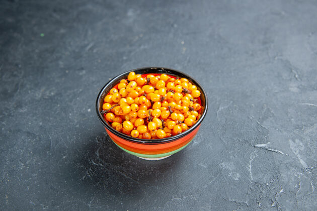 种子前视沙棘在碗里暗红色的表面上自由摆放碗景观金橘