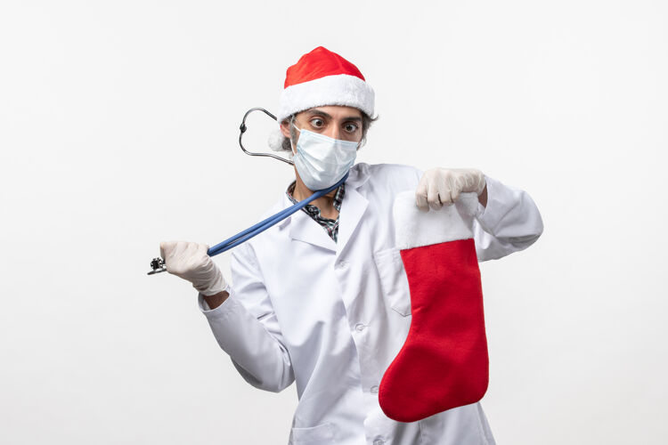圣诞节正面图：男医生在观察白墙上的节日袜子病毒可以保护节日健康高尔夫球手视图男医生