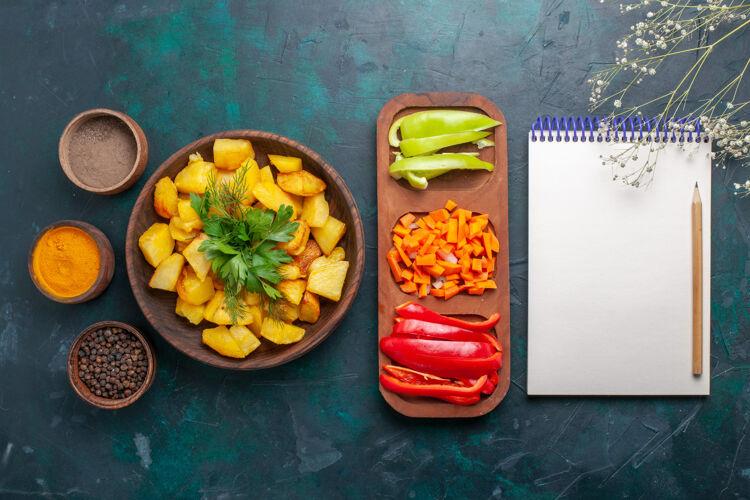一餐俯视图煮熟的土豆 配上蔬菜 调味料和深蓝色的辣椒片青豆切片胡椒粉