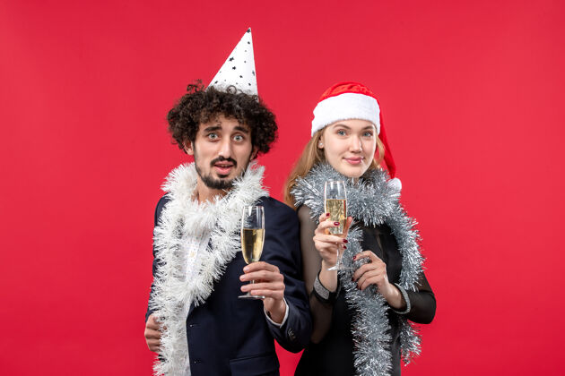 肖像前视图年轻夫妇刚刚庆祝新年红墙彩色圣诞爱情派对颜色圣诞节帽子
