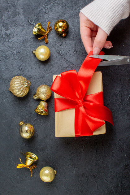 圣诞节礼品盒上手工切割的红丝带和深色背景上的装饰配件的垂直视图头发幻灯片剪辑削减