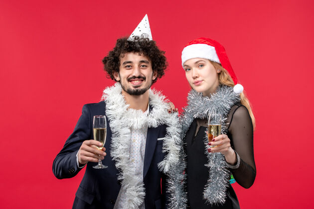 年轻夫妇正面图年轻夫妇在红墙上庆祝新年节日圣诞之爱圣诞风景成人