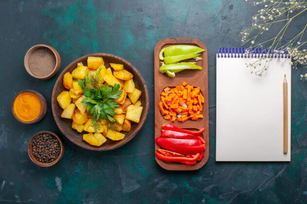 一餐俯视图煮熟的土豆 配上蔬菜 调味料和深蓝色的辣椒片青豆切片胡椒粉