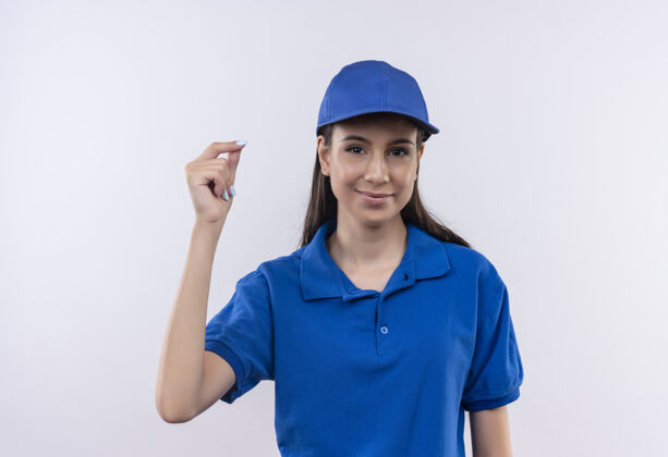 递送穿着蓝色制服 戴着帽子的年轻送货女孩在赚钱 脸上带着微笑 手搓手指帽子年轻女孩