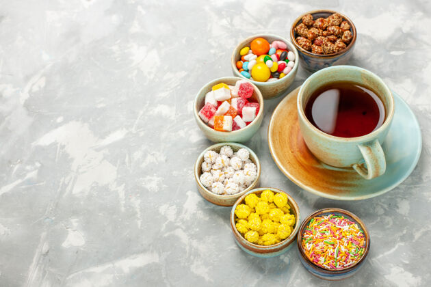 食物不同的糖果棉花糖和一杯茶放在白色的桌子上不同美味美食