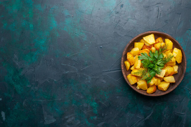 蔬菜俯视图烹饪土豆片与绿色内棕色盘子在深蓝色的表面土豆健康内部