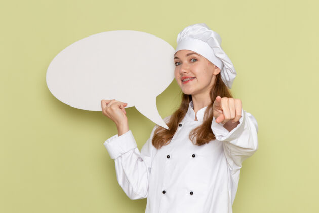 医生身着白色厨师服的女厨师手持绿色墙壁上的白色大标牌的正面视图厨房大专业