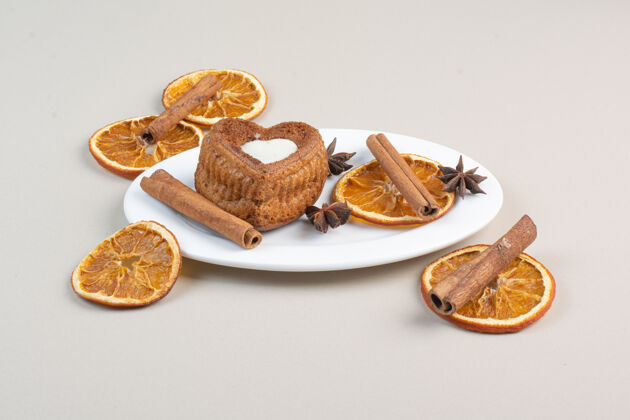 肉桂心形蛋糕 橘子片 丁香和肉桂放在白色盘子里切片美味蛋糕