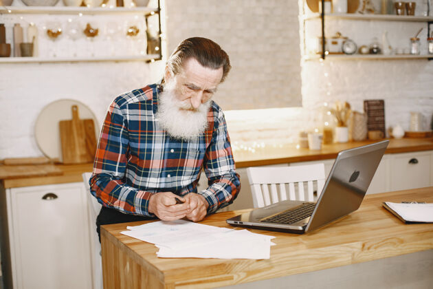 桌子老人拿着笔记本电脑爷爷坐在圣诞装饰品里无线年龄通信