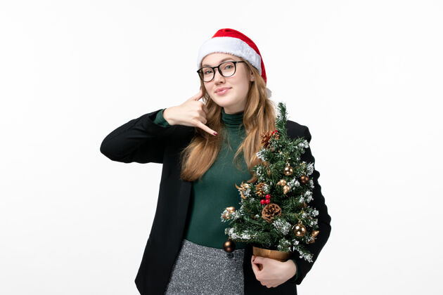美丽正面图年轻女子手持白色墙上的圣诞树玩具新年圣诞圣诞成人年轻女性