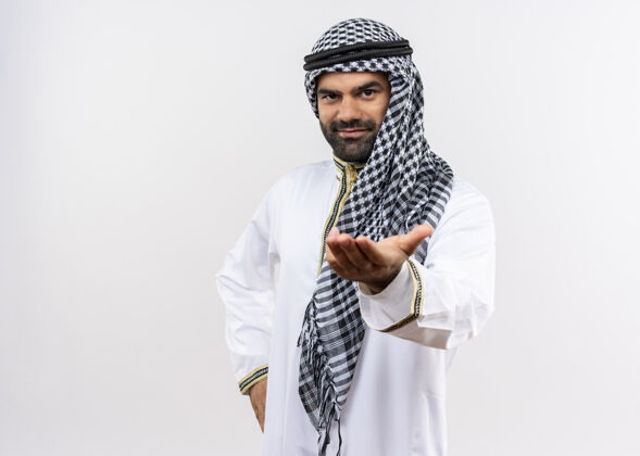 站身着传统服装的阿拉伯男子面带微笑 站在白色墙壁上举手致意手穿问候